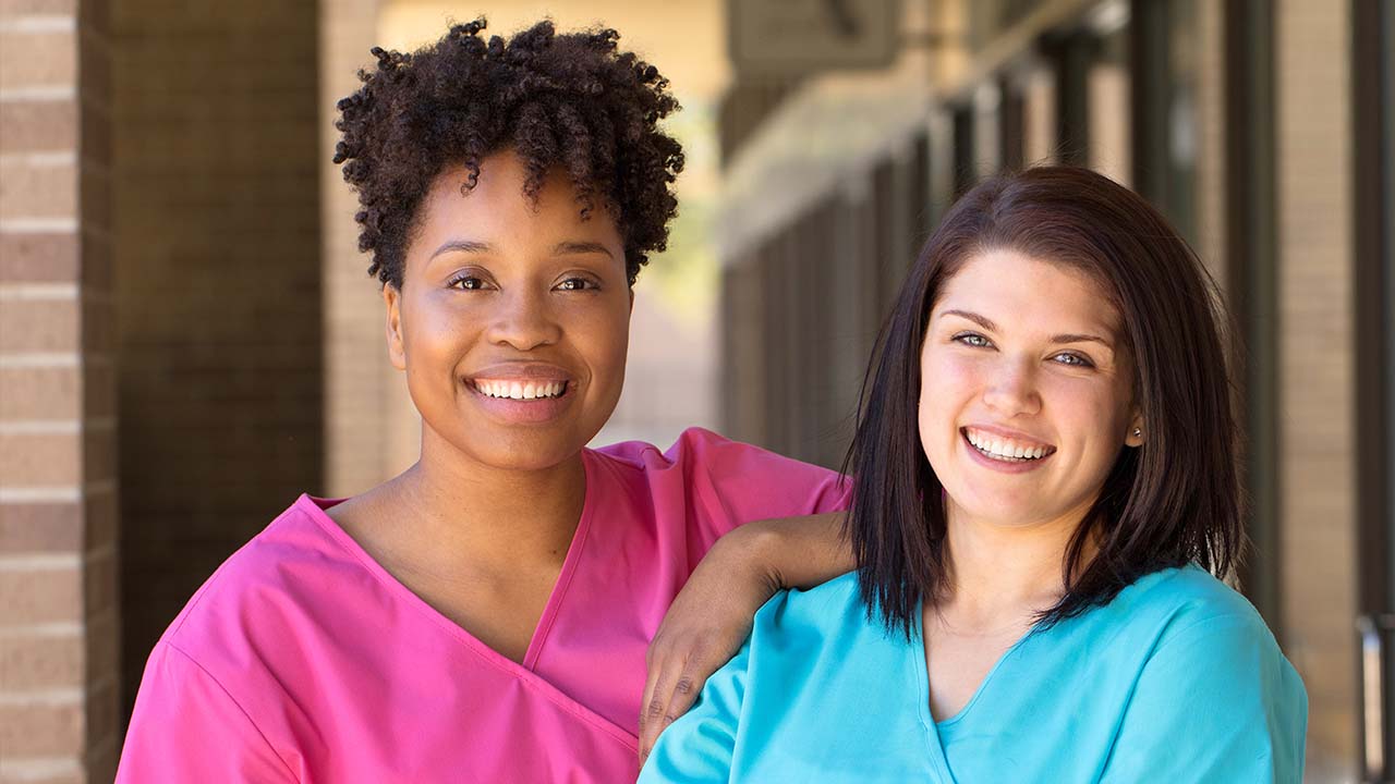 two weight loss doctors in scrubs outside the clinic pose for a photo