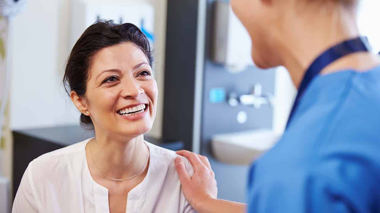 a client sits on teh exam table discussing the weight loss program with the doctor