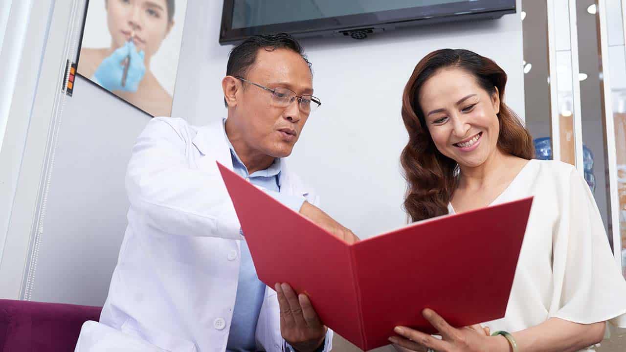 a client reviews her medical history with a doctor holding her chart